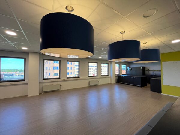 Moderne, lege kantoorruimte aan de Barchman Wuytierslaan met grote ramen, blauwe hanglampen en een kitchenette.